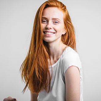 A red-haired girl smiling against a white background