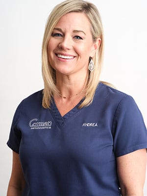 A blonde woman in navy blue scrubs against a white background