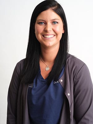A black haired woman in navy blue scrubs against a white background
