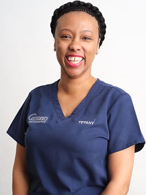 A black haired woman in navy blue scrubs against a white background