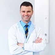 A man with a blue shirt, tie, and white lab coat.