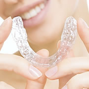 A close up of a woman holding up a clear aligner.