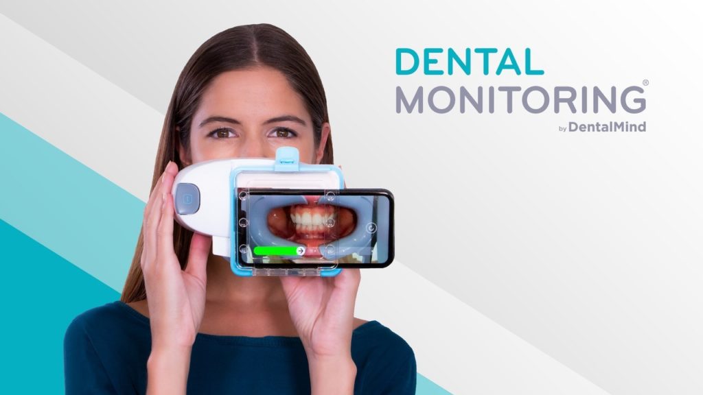 A woman is holding up a phone with the text dental monitoring.