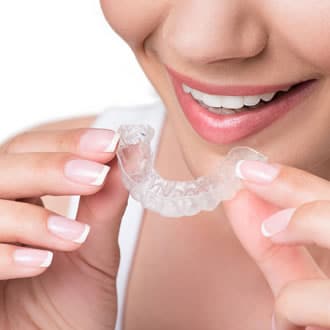 Close-up of a woman holding up a clear aligner