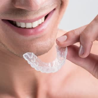 Close-up of a man holding up a clear aligner