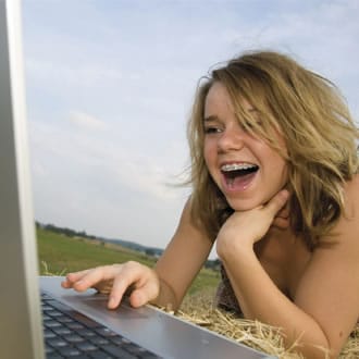 A girl with braces using her computer in the middle of a field
