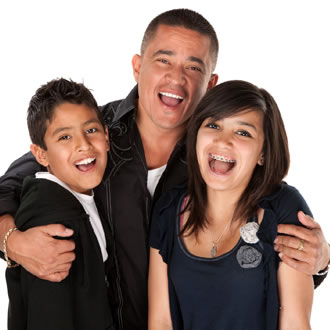 A man and two kids wearing black and smiling together against a white background.