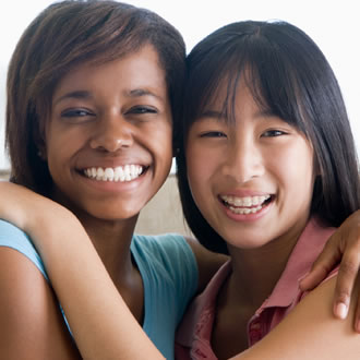 Two girls smiling with their arms around each other