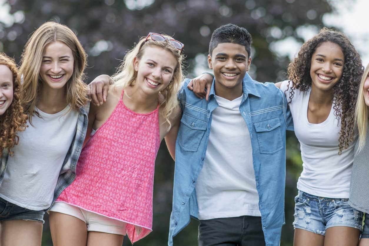 Groups of 6 teenagers with arms around their shoulders smiling with healthy, aligned, bites