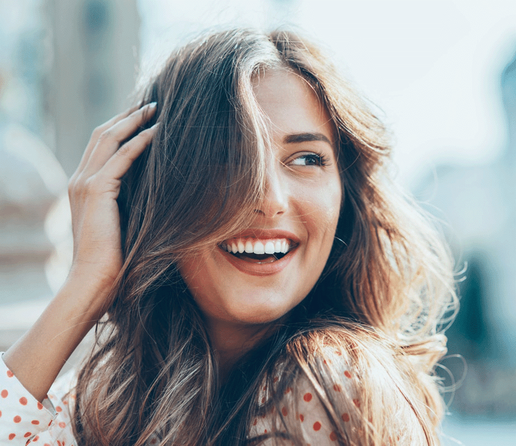 A woman smiling while running her hand through her hair.