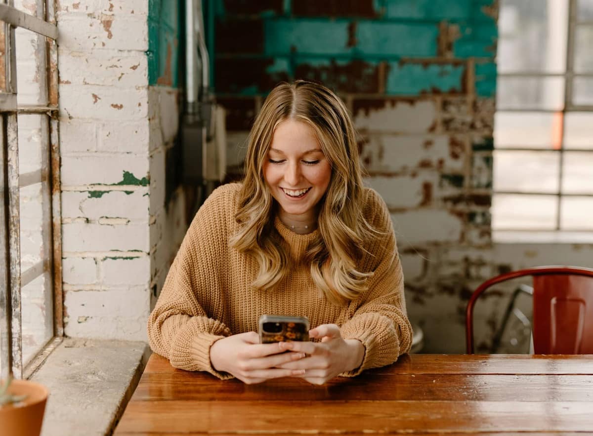 Woman in a rustic cafe leaving a sparkling review for her orthodontic treatment