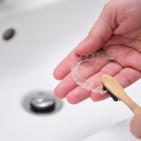 Cleaning tooth aligners. Washing and removing organic residues with a bamboo toothbrush from orthodontic invisible braces.